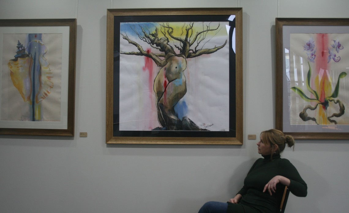 Deirdre McCrimmon sitting by three pieces of her art