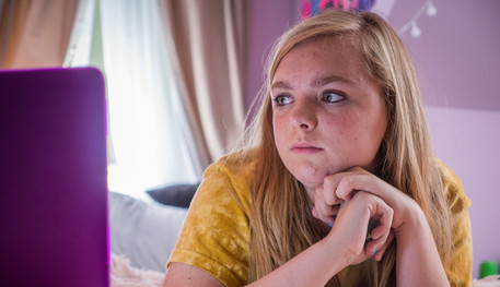 Image of a young girl staring at a computer screen