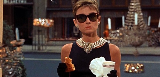 Picture of a lady holding a croissant and a coffee cup in her hands